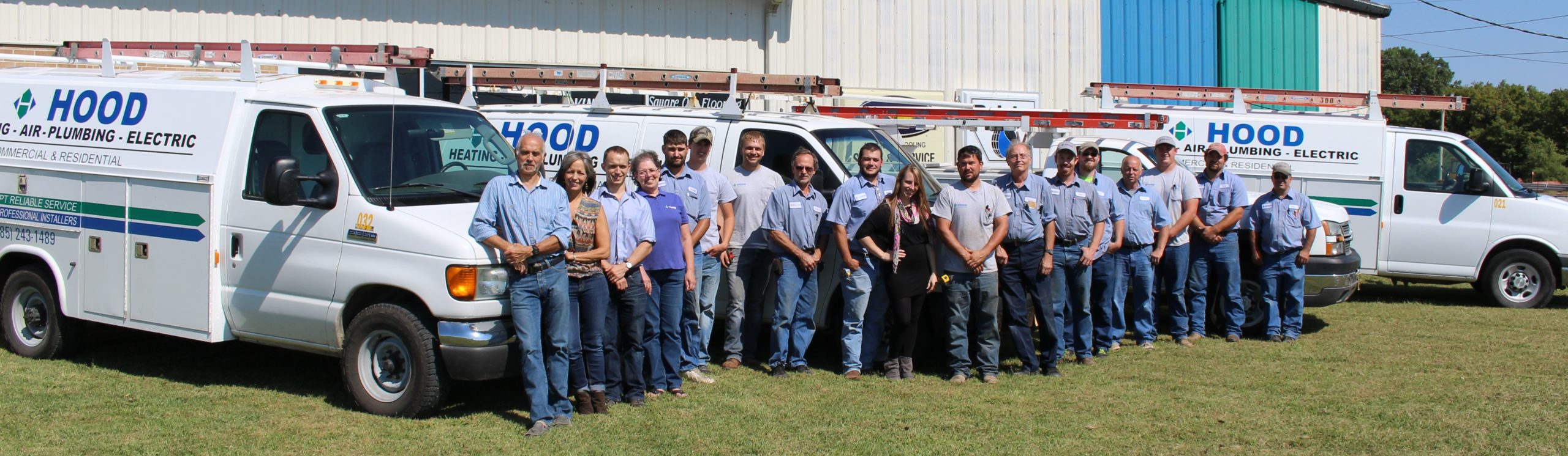 The Hood Heating Air Plumbing and Electric team — approximately 18 technicians standing in front of Hood-branded service vans